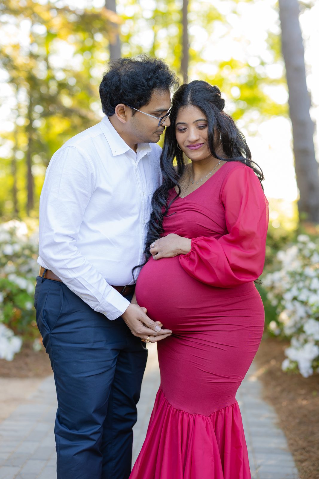 Maternity couple in greenery, magenta gown