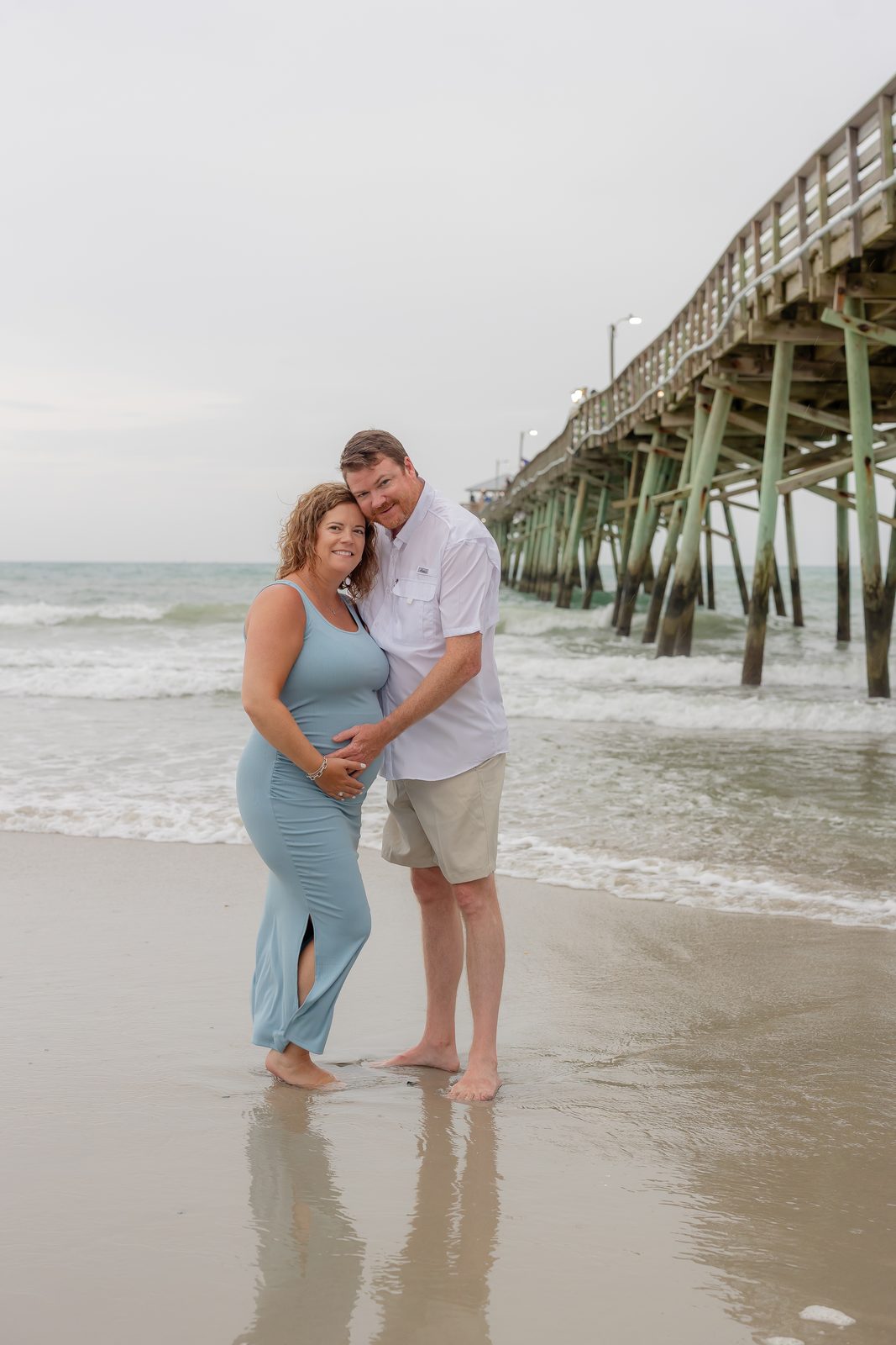 Maternity couple at beach pier in blue dress