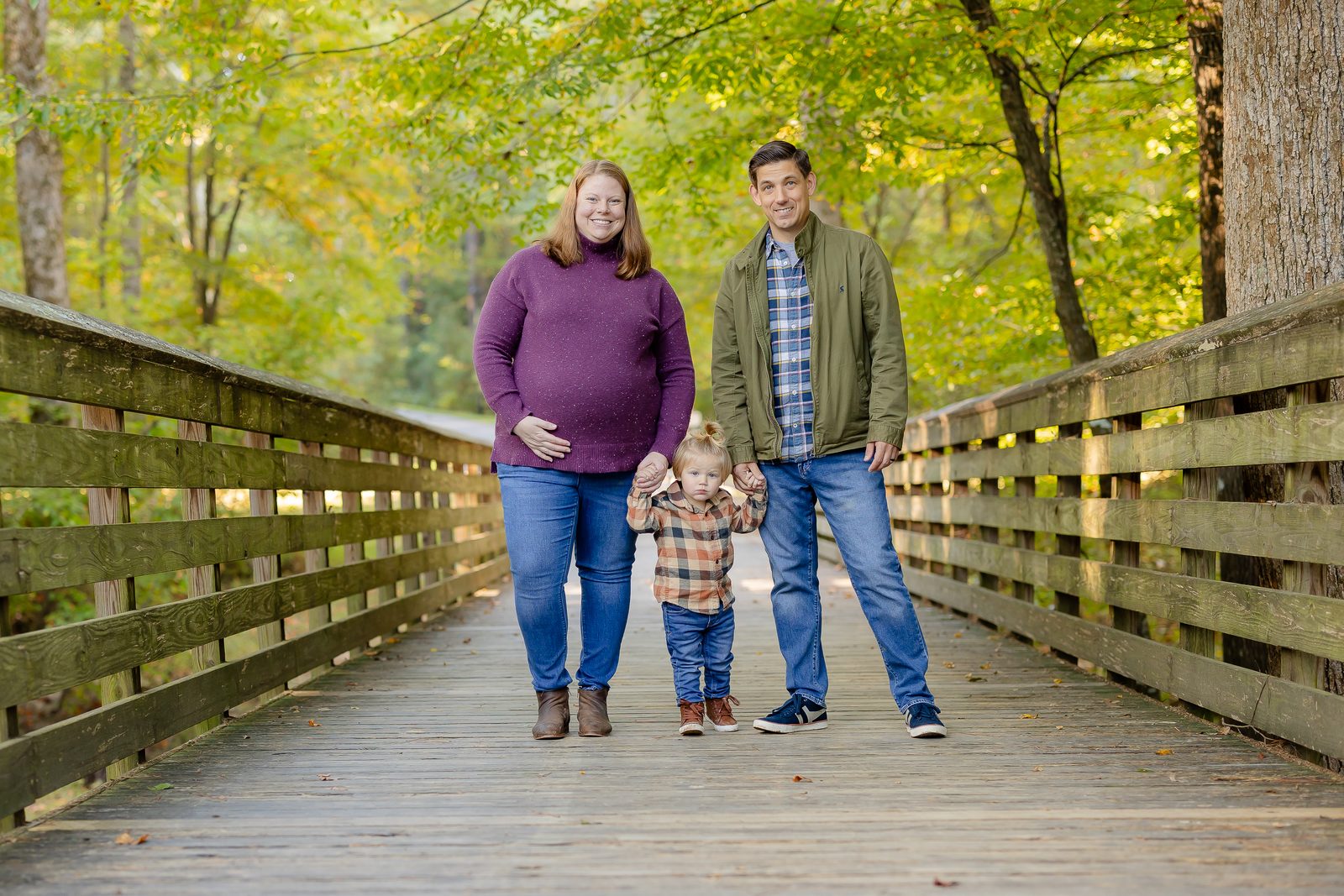 Maternity family on wooden bridge with toddler