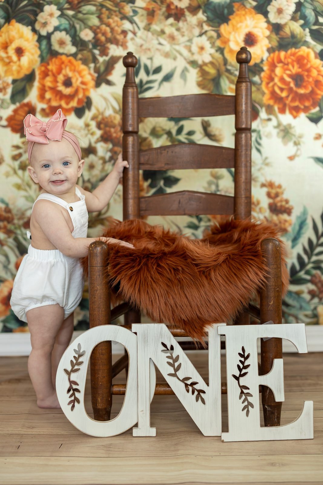 First birthday session with floral backdrop and ONE letters