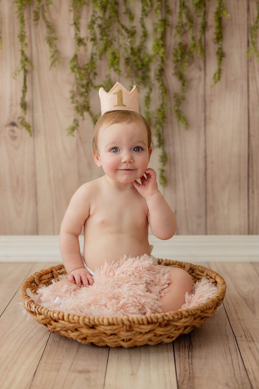One-year-old with gold crown in pink basket